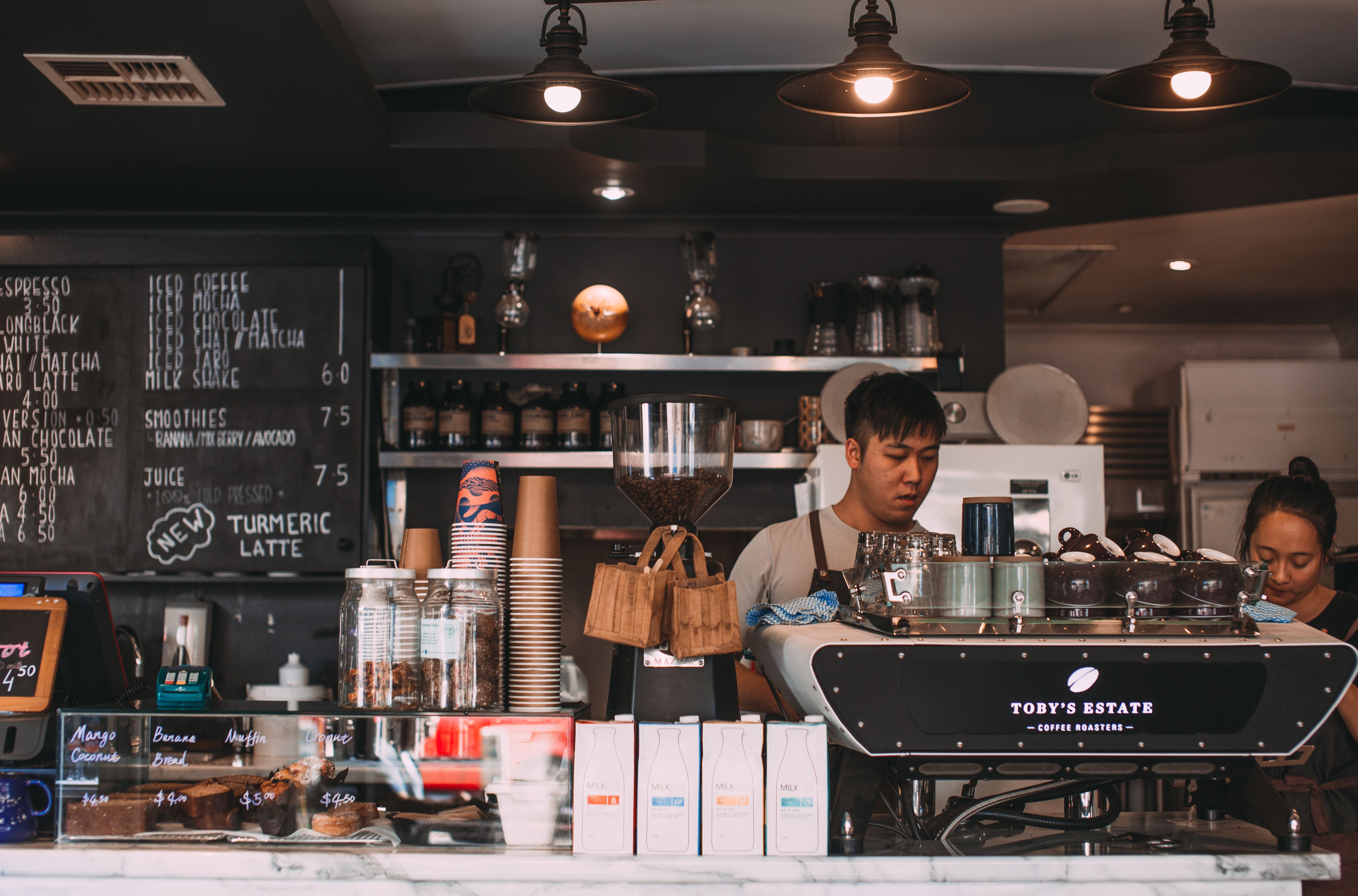 Busy coffee shop counter during morning rush with customers waiting in line